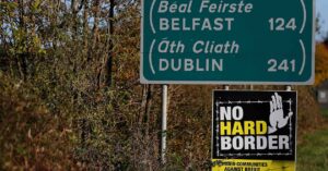 Road sign indicating Belfast and Dublin with a "no hard border" protestor sign under